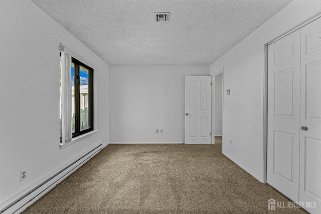 carpeted empty room featuring a textured ceiling and a baseboard heating unit