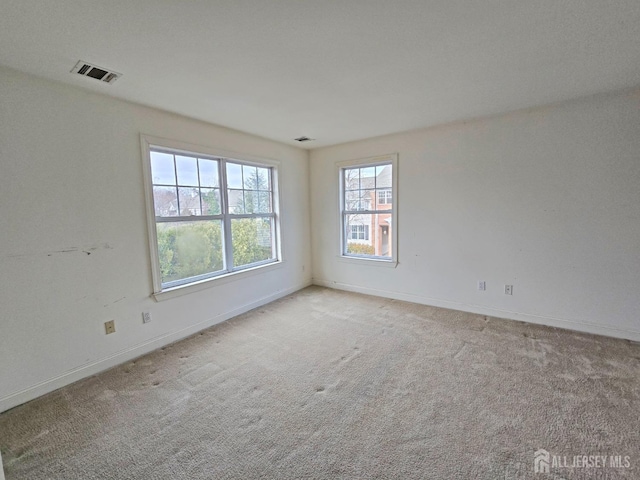 empty room featuring carpet floors, visible vents, and baseboards