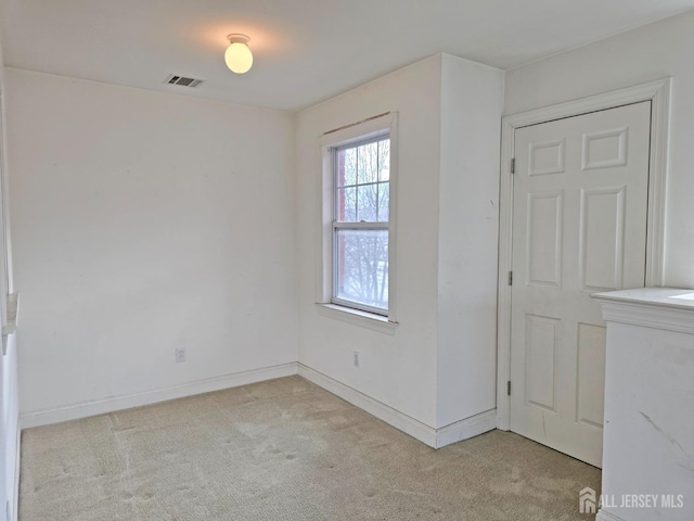 unfurnished room with baseboards, visible vents, and light colored carpet