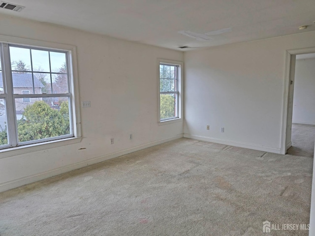 spare room with carpet, visible vents, and baseboards