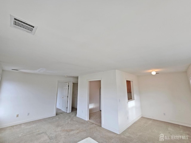 empty room featuring light carpet, visible vents, and baseboards