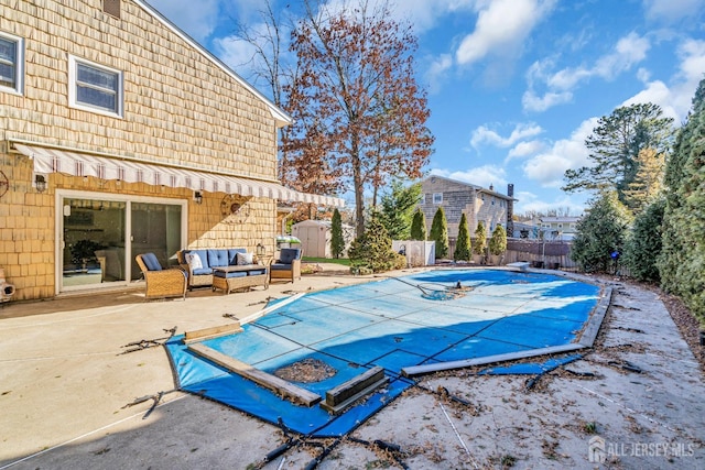 view of pool with a covered pool, a patio, a fenced backyard, outdoor lounge area, and a diving board