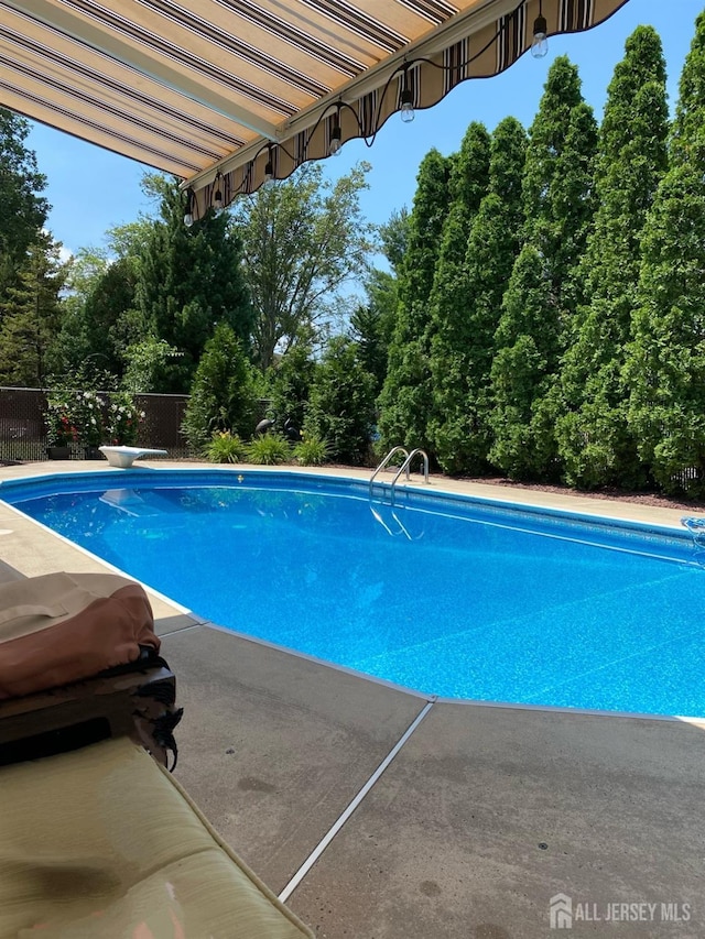 outdoor pool featuring a diving board and fence