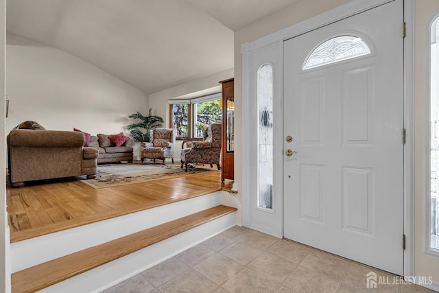 foyer entrance with light tile patterned floors and lofted ceiling