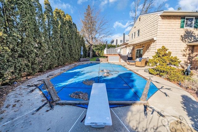 view of pool with a covered pool, a patio, a diving board, and a wooden deck