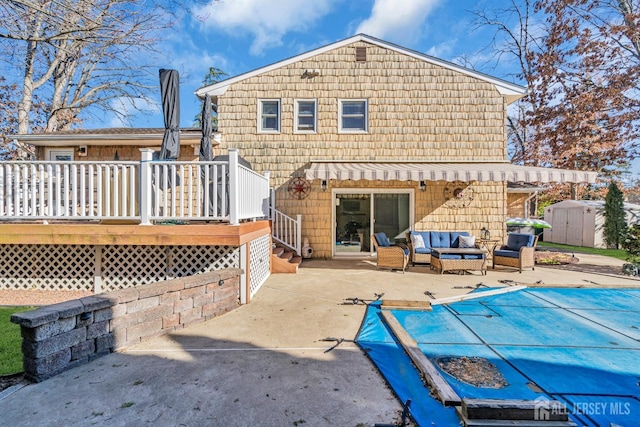 rear view of house with a patio, a shed, a covered pool, an outdoor living space, and a deck