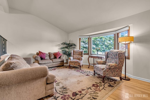 living room featuring baseboards, lofted ceiling, and wood finished floors