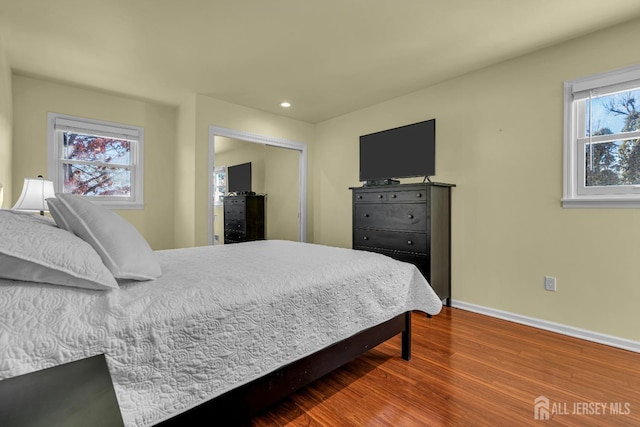 bedroom featuring recessed lighting, wood finished floors, baseboards, and a closet