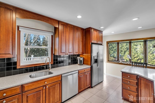 kitchen featuring a sink, light tile patterned flooring, a healthy amount of sunlight, and stainless steel appliances