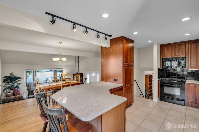 kitchen featuring a notable chandelier, black appliances, a breakfast bar area, brown cabinetry, and decorative backsplash