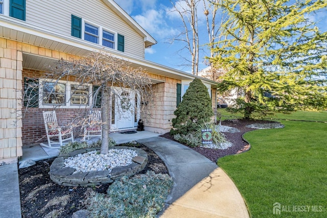 doorway to property featuring a lawn and a porch