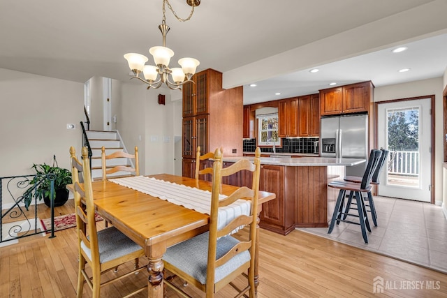 dining room featuring recessed lighting, light wood-type flooring, an inviting chandelier, and stairs