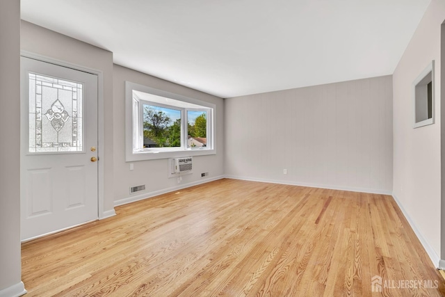 foyer featuring baseboards, visible vents, a wall mounted air conditioner, and light wood-style floors