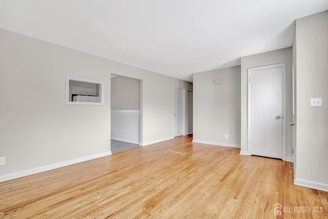empty room with baseboards and light wood-type flooring
