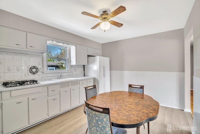 kitchen with light wood-style floors, a ceiling fan, light countertops, freestanding refrigerator, and stainless steel gas stovetop