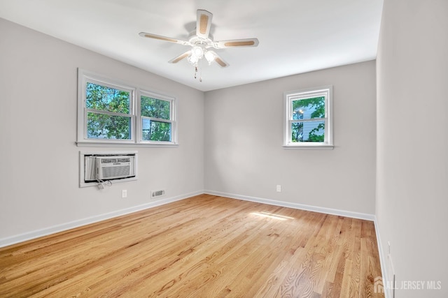 unfurnished room featuring light wood-type flooring, baseboards, a wall unit AC, and a healthy amount of sunlight