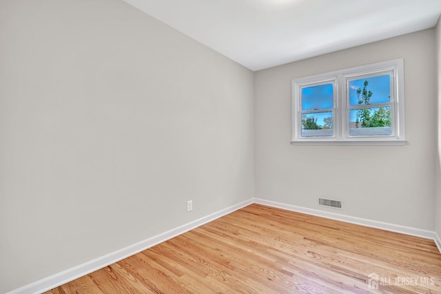 spare room featuring baseboards, visible vents, and light wood-type flooring