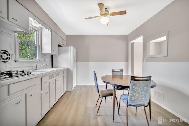 kitchen featuring gas cooktop, a ceiling fan, visible vents, a sink, and freestanding refrigerator
