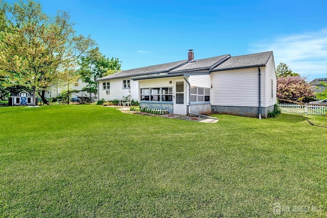 rear view of property with fence, a sunroom, a chimney, and a yard