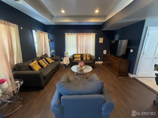 living room with dark wood-type flooring and a tray ceiling