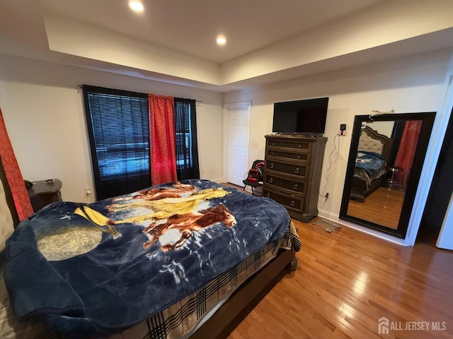 bedroom with hardwood / wood-style flooring and a tray ceiling