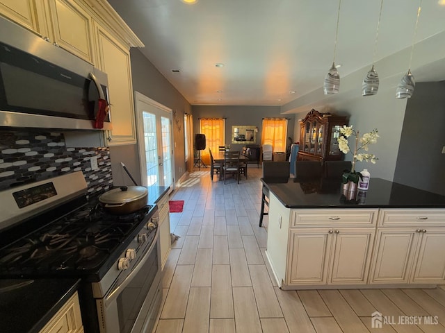 kitchen featuring french doors, decorative light fixtures, backsplash, stainless steel appliances, and cream cabinetry