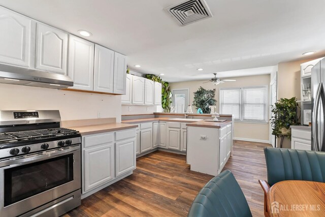 kitchen with ceiling fan, extractor fan, dark hardwood / wood-style flooring, white cabinetry, and stainless steel range with gas cooktop