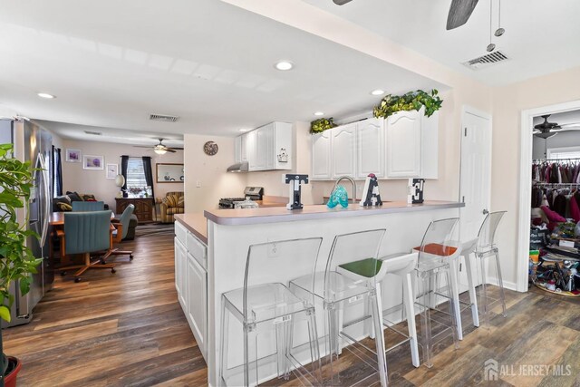 kitchen featuring stainless steel range, kitchen peninsula, sink, white cabinetry, and dark hardwood / wood-style flooring