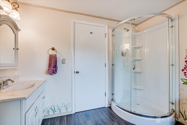 bathroom featuring a stall shower, wood finished floors, vanity, and crown molding