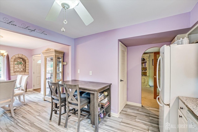 dining space featuring arched walkways, baseboards, and a skylight