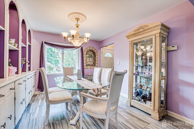 dining area with a chandelier, baseboards, and wood finish floors