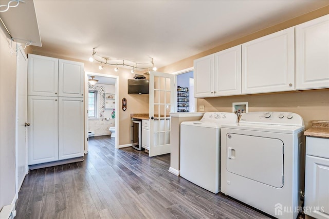 washroom featuring cabinet space, independent washer and dryer, wood finished floors, and baseboards