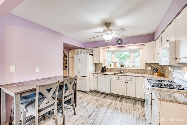 kitchen featuring white appliances, a sink, ceiling fan, tasteful backsplash, and white cabinets