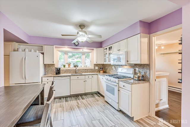 kitchen with white appliances, a ceiling fan, tasteful backsplash, white cabinetry, and a sink