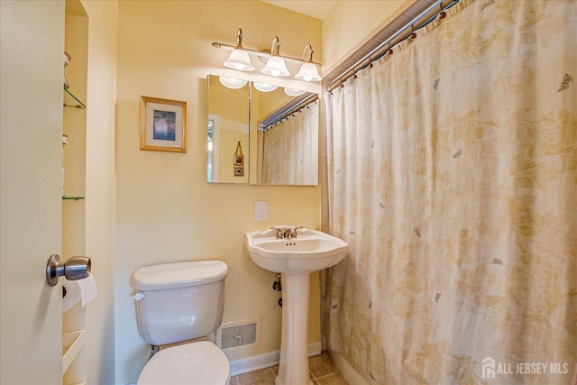bathroom featuring toilet, tile patterned flooring, baseboards, a sink, and a shower with curtain