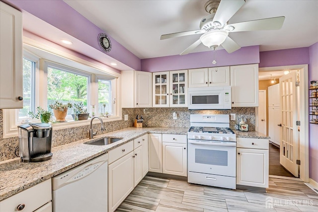 kitchen with white appliances, a sink, white cabinetry, and tasteful backsplash