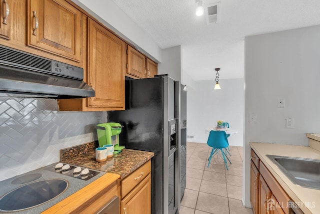 kitchen with cooktop, visible vents, brown cabinets, hanging light fixtures, and under cabinet range hood