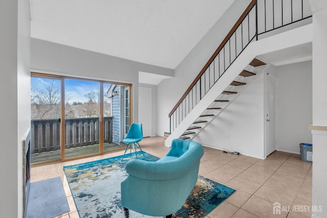 sitting room with a high ceiling, light tile patterned flooring, baseboards, and stairs