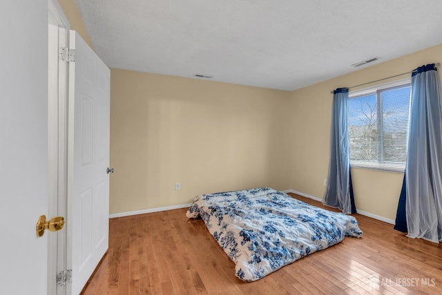 bedroom with visible vents, light wood-style flooring, and baseboards