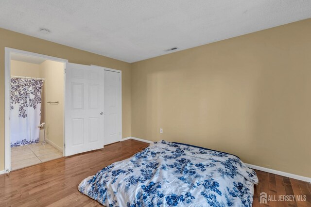 bedroom with visible vents, baseboards, and wood finished floors