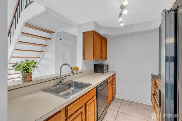 kitchen featuring brown cabinetry, appliances with stainless steel finishes, light countertops, a textured ceiling, and a sink