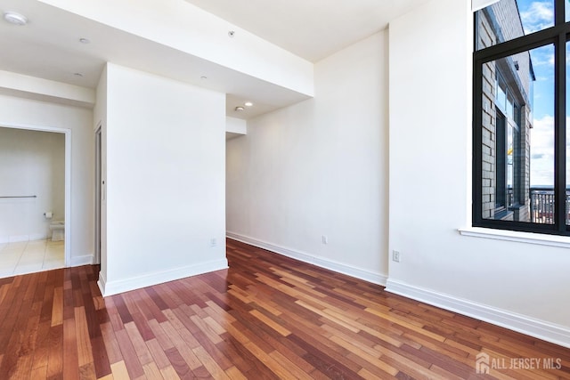 spare room with baseboards and hardwood / wood-style floors