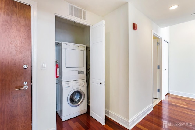 laundry room featuring laundry area, dark wood-style floors, visible vents, and stacked washer and clothes dryer