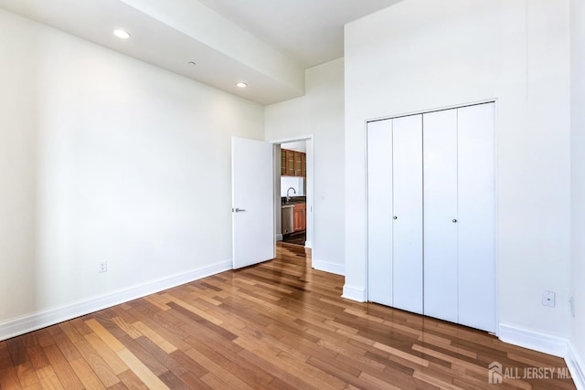 unfurnished bedroom with baseboards, wood finished floors, and recessed lighting