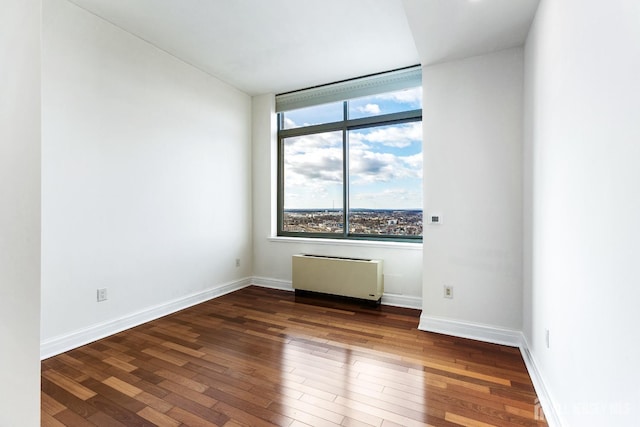 unfurnished room featuring hardwood / wood-style flooring, radiator heating unit, and baseboards