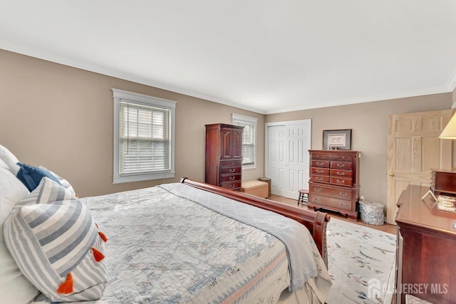 bedroom featuring crown molding, a closet, and wood finished floors