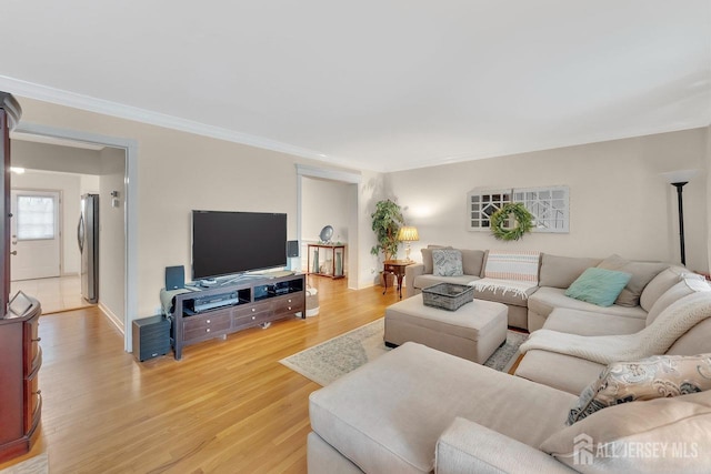 living room with crown molding, baseboards, and light wood-type flooring