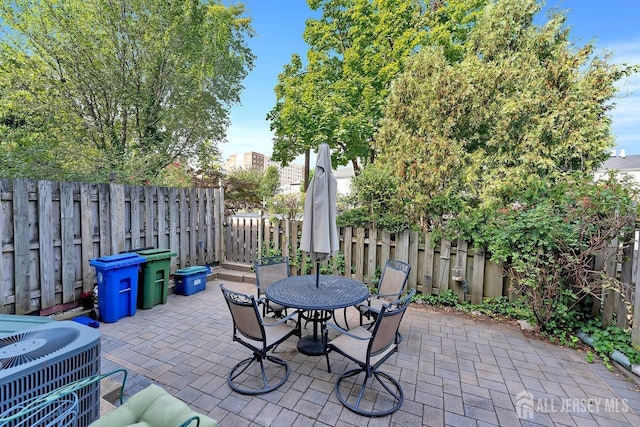 view of patio with central air condition unit, outdoor dining space, and a fenced backyard