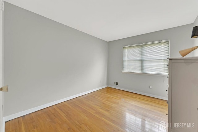 spare room with baseboards, light wood finished floors, and visible vents