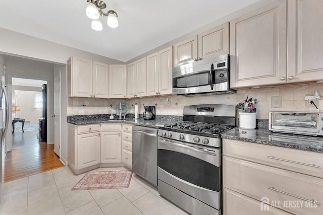 kitchen with decorative backsplash, light tile patterned floors, a toaster, and stainless steel appliances